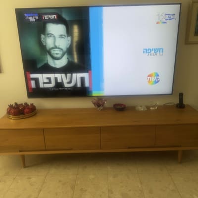 תליית טלוויזיה על הקיר מעל מזנון עץ בסלון