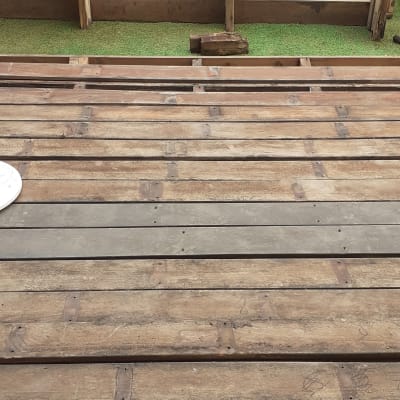 משטח עץ עם קורות עץ, עציץ ופרחים ברקע