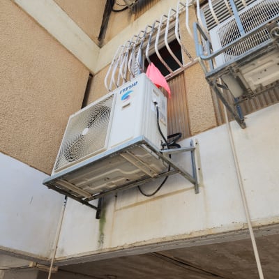 מעבה של מזגן טורנדו מותקן על תושבת מתכת בקיר חיצוני