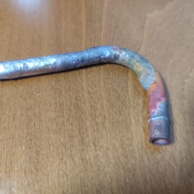 צינור מתכת מעוקל על שולחן עץ