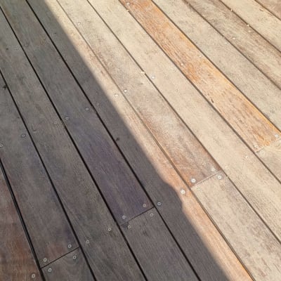 דק עץ עם ברגים בגינה מוארת בשמש