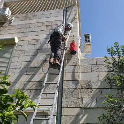 אדם על סולם ליד קיר עם צינור ואביזרים