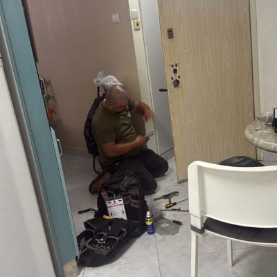 אדם עובד על דלת עם כלים לתיקון מנעולים