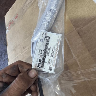 חלק חילוף לרכב עם תווית יצרן, יד מלוכלכת מחזיקה את החלק.