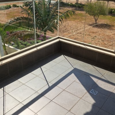 מרפסת נקייה עם ריצוף גרניט פורצלן ומעקה זכוכית שקוף