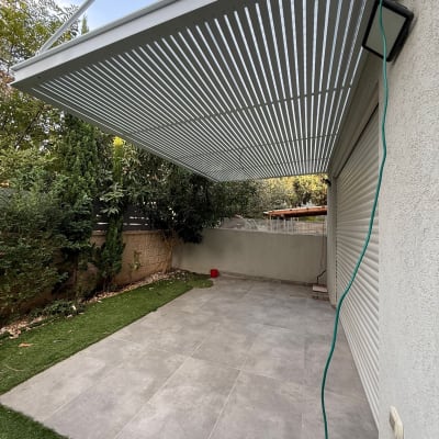 פרגולה אלומיניום מותקנת בחצר עם דשא וריצוף אפור