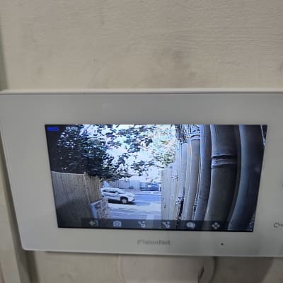 מסך אינטרקום פנימי מותקן על קיר ומציג תמונה ממצלמת כניסה