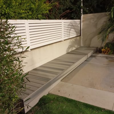 ספסל עץ ליד גדר לבנה בגינה