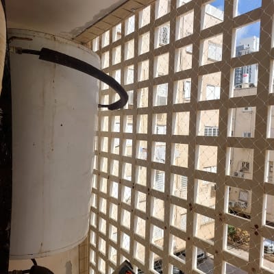 רשת יונים מותקנת על מרפסת עם דוד שמש