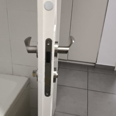 ידית דלת מתכתית על דלת לבנה בחדר אמבטיה