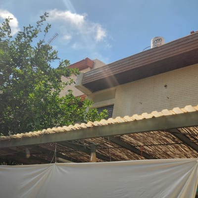 מבט מלמטה על חזית בניין מגורים, פרגולה ובד לבן