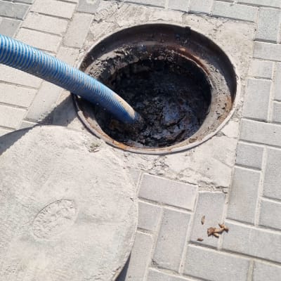 צינור שואב בתוך פתח ביוב על מדרכה