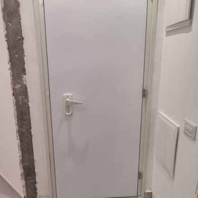 דלת לבנה עם ידית כסופה במסגרת קיר