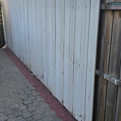 גדר עץ צבועה בלבן עם מברגה על הקרקע