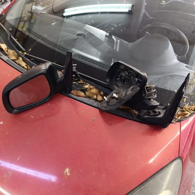 מראה צד שבורה על מכסה מנוע של רכב אדום