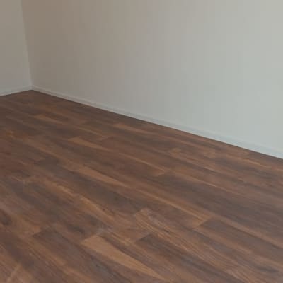 רצפת פרקט עץ כהה בחדר ריק עם קירות לבנים