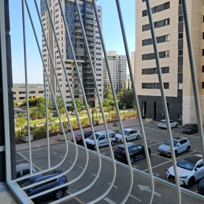 בניינים גבוהים ומכוניות חונות מאחורי סורגים