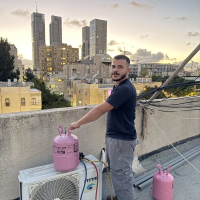 אדם עומד ליד מזגן עם בלון גז על גג