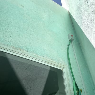 קופסת חשמל עם כבל ירוק על קיר חיצוני