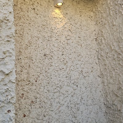 מנורת קיר לבנה דולקת על קיר מחוספס