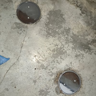 שני מכסי ביוב עגולים על רצפת בטון סדוקה