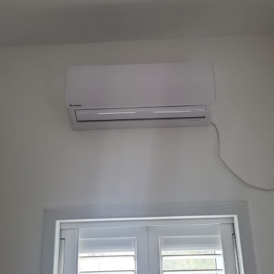 מזגן מותקן על קיר לבן עם שקע חשמל