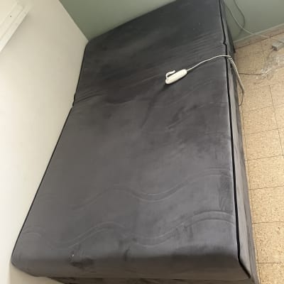 מיטה אפורה עם שלט על רצפת אריחים