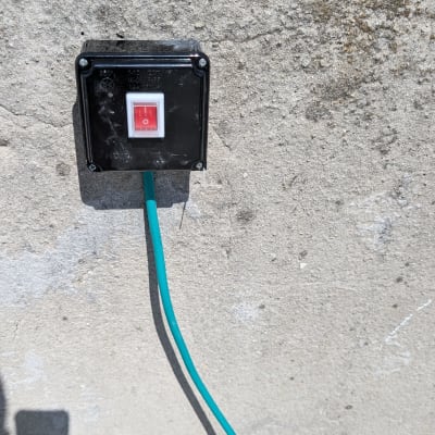 שקע חשמלי עם כבל ירוק על קיר בטון