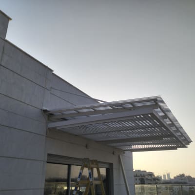 פרגולה מתכתית מותקנת על קיר חיצוני של מבנה