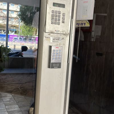 אינטרקום עם מצלמה ומקשים על קיר ליד דלת