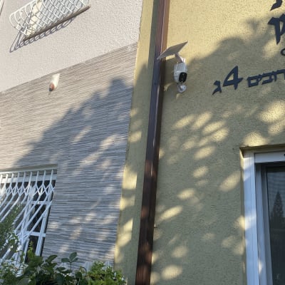 קיר חיצוני עם מצלמת אבטחה וסוללה סולארית