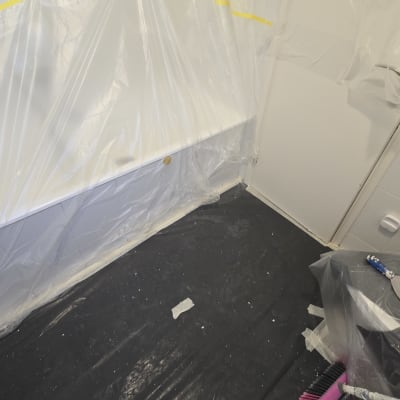 רצפה מכוסה בניילון, מברשת צבע ורגל עם מכנסיים לבנים