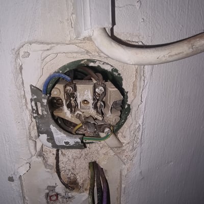 חוטי חשמל חשופים בקופסת חיבורים בקיר