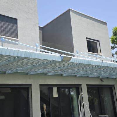 פרגולה מאלומיניום מחוברת לקיר חיצוני של בית