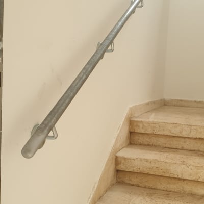מעקה מתכת צמוד לקיר מעל מדרגות אבן