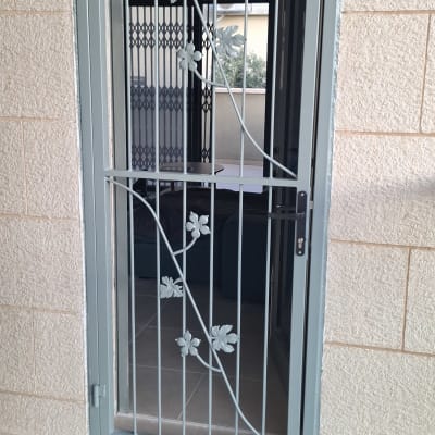 סורג ישר ממתכת נפתח עם עיטורי פרחים ועלים בחלון