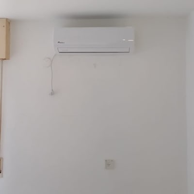 מזגן מותקן על קיר לבן עם חוט חשמל