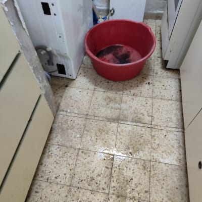 דליפה על הרצפה ליד מכונת כביסה ודלי אדום