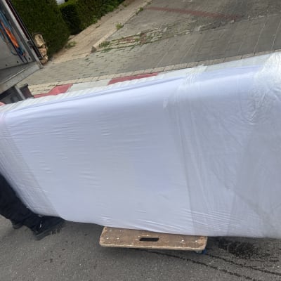 מזרן עטוף בניילון על עגלה ליד משאית