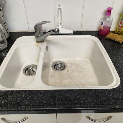 כיור מטבח עם ברז, בקבוקי סבון וכלים