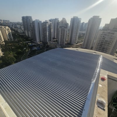 גג מתכת על בניין גבוה עם נוף עירוני ברקע
