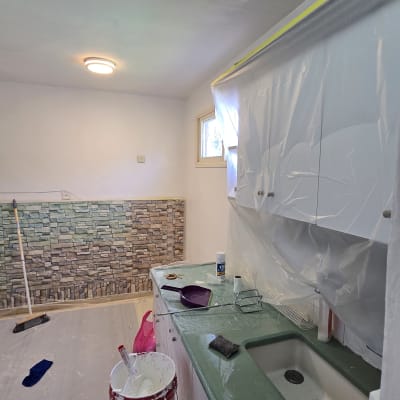 פחיות צבע ומברשת על רצפה מכוסה בניילון