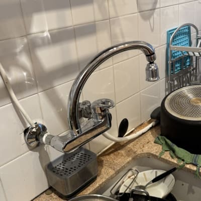 ברז מטבח עם צינור מים לבן על קיר אריחים