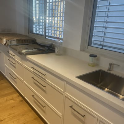 מטבח נקי עם כיור, חלונות וחומרי ניקוי