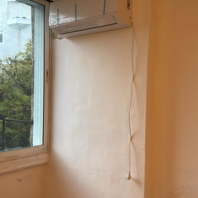 מזגן מותקן על קיר ליד חלון עם כבל חשמל