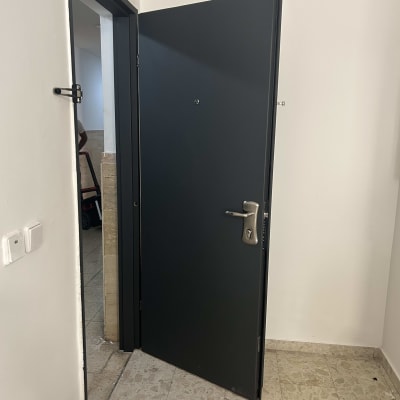 דלת מתכת כהה עם ידית כסופה פתוחה למחצה