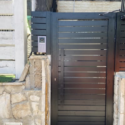 אינטרקום עם לוח מקשים ליד שער מתכת שחור