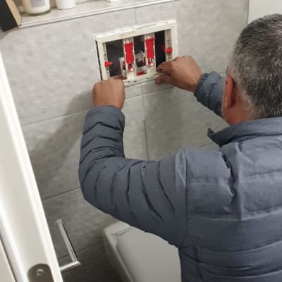 אדם מתקן מערכת מים בקיר חדר אמבטיה