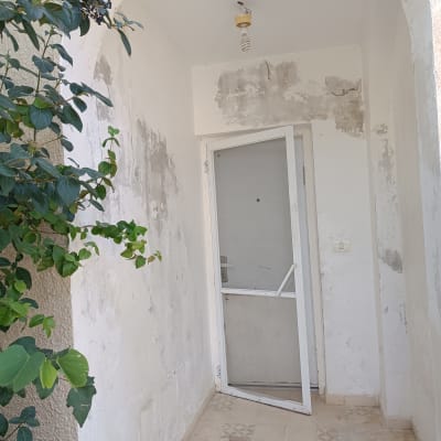 קיר צבוע עם דלת פתוחה וחומרי צביעה על הרצפה