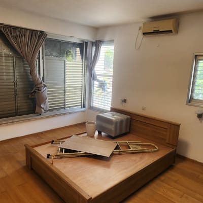 חדר עם מיטה, לוחות עץ וכלי עבודה על הרצפה